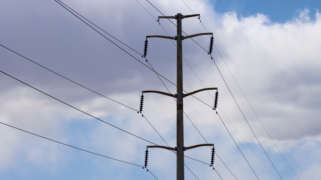Overhead High Voltage Transmission lines blowing in the wind as clouds rumble in the background in this 4k timelapse
