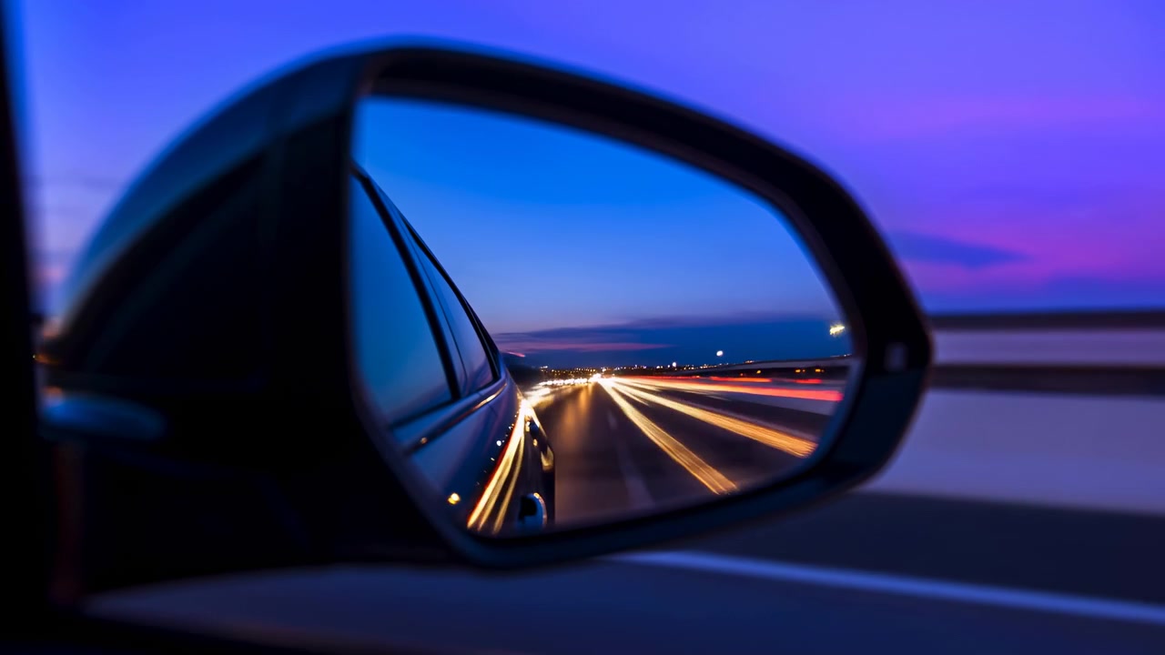 Una vista centrale da un'auto in movimento cattura la frenesia dell'autostrada e uno skyline cittadino lontano al crepuscolo.