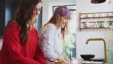 gay female couple at home in kitchen washing up and drinking wine after dinner on christmas day