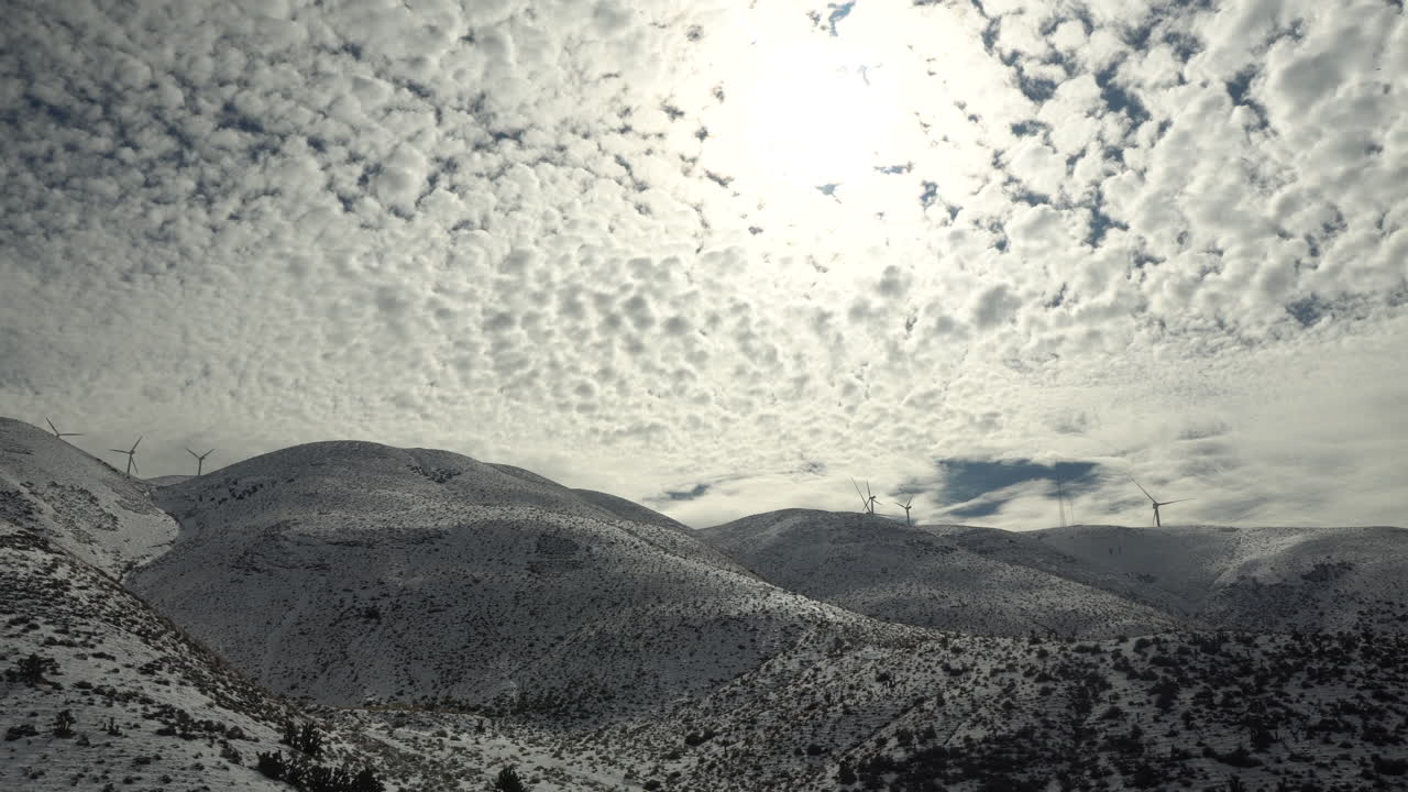 nubes esponjosas llenan todo el cielo y se desplazan sobre montañas cubiertas de nieve