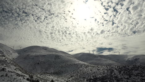 Fluffy-clouds-fill-entire-sky-and-drift-over-snow-covered-mountains