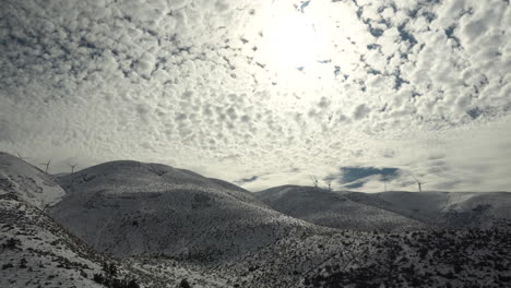 毛茸茸的云彩填滿了整個天空, 漂浮在雪覆蓋的山上.