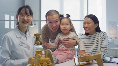 portrait of happy asian family and pediatrician in clinic