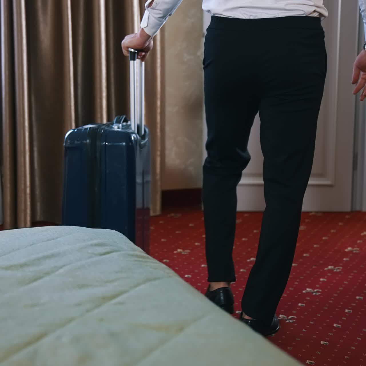 Man with suitcase leaving the room. Businessman in black trousers taking his luggage and moving to the door in the hotel. The end of business journey