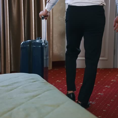 man with suitcase leaving the room. businessman in black trousers taking his luggage and moving to the door in the hotel. the end of business journey