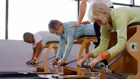 trainer assisting senior women to exercise 4k