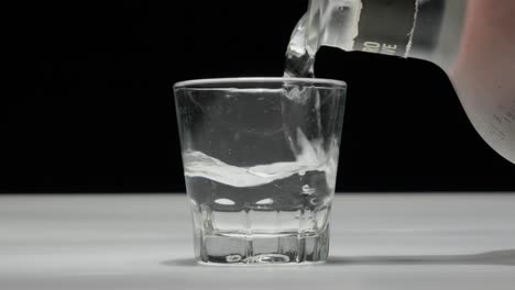 Transparent-drink-pouring-into-a-glass,-white-background,-close-up