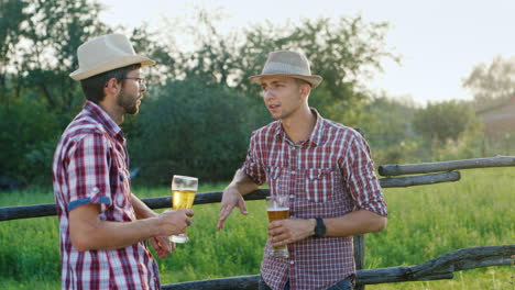 two farmers drink beer at a fence of their ranch