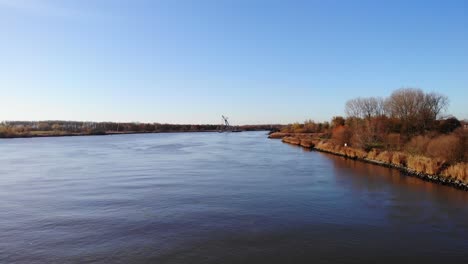 aerial dolly left across oude maas lined with autumnal trees