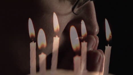 animation of burning candles over man praying on black background