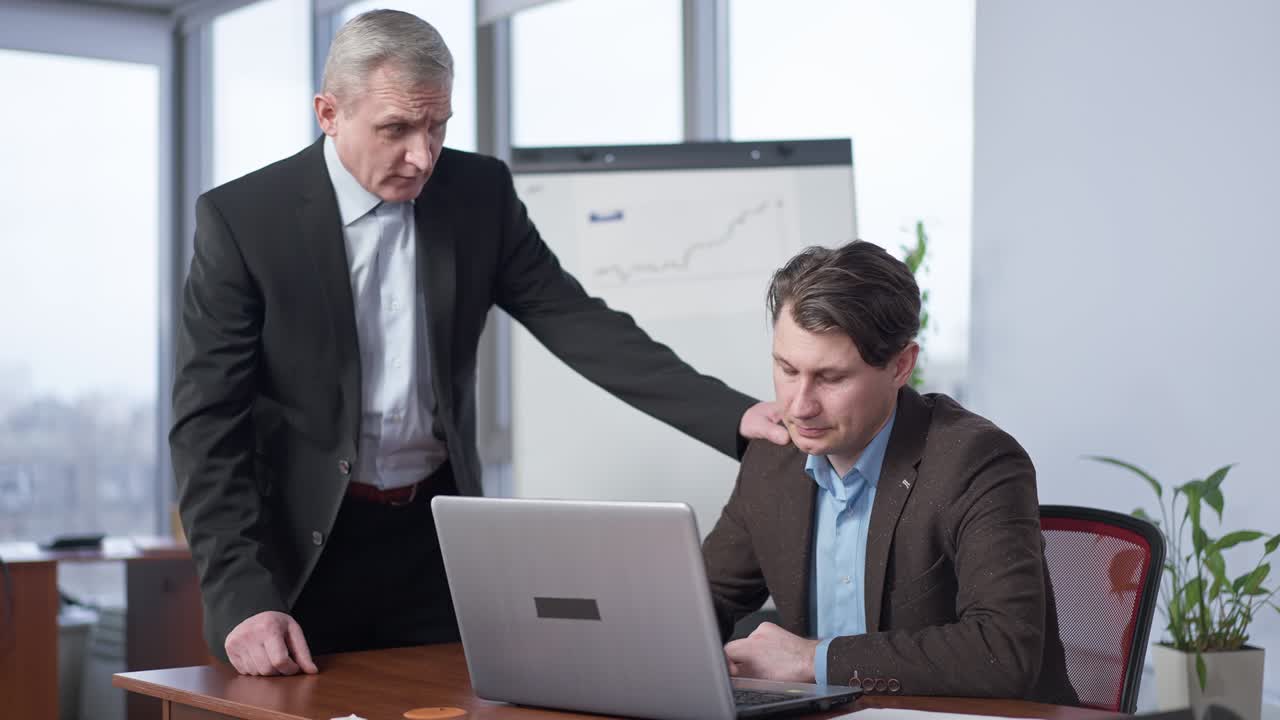 портрет старшего кавказского исполнительного директора-мужчины, поддерживающего молодого сотрудника в офисе. позитивный человек успокаивает напряженного коллегу в помещении. бизнес-сотрудничество и партнерская поддержка.