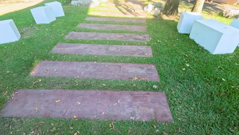 a serene pathway with stone slabs and benches in a sunlit park setting, captured in bangkok, thailand