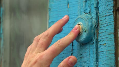 woman pressing the doorbell button on the old blue door 02