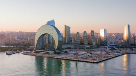 Flying-along-the-coastline-of-Baku-city-built-up-with-modern-glass-skyscrapers,-Azerbaijan