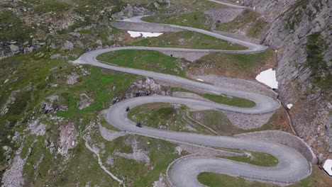 winding alpine road cutting through rocky terrain with remnants of snow along edges