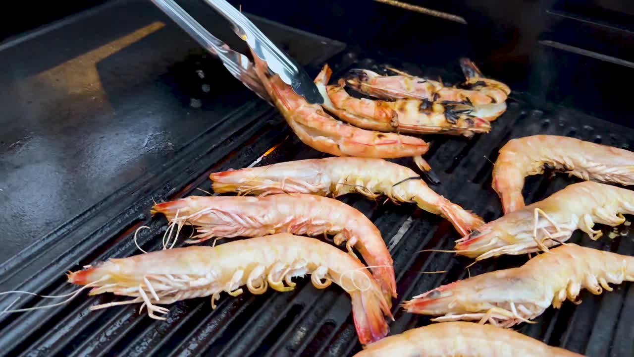 Prawns being grilled with tongs on barbecue