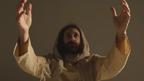 portrait of man wearing robes with long hair and beard representing figure of jesus christ raising hands in prayer 2