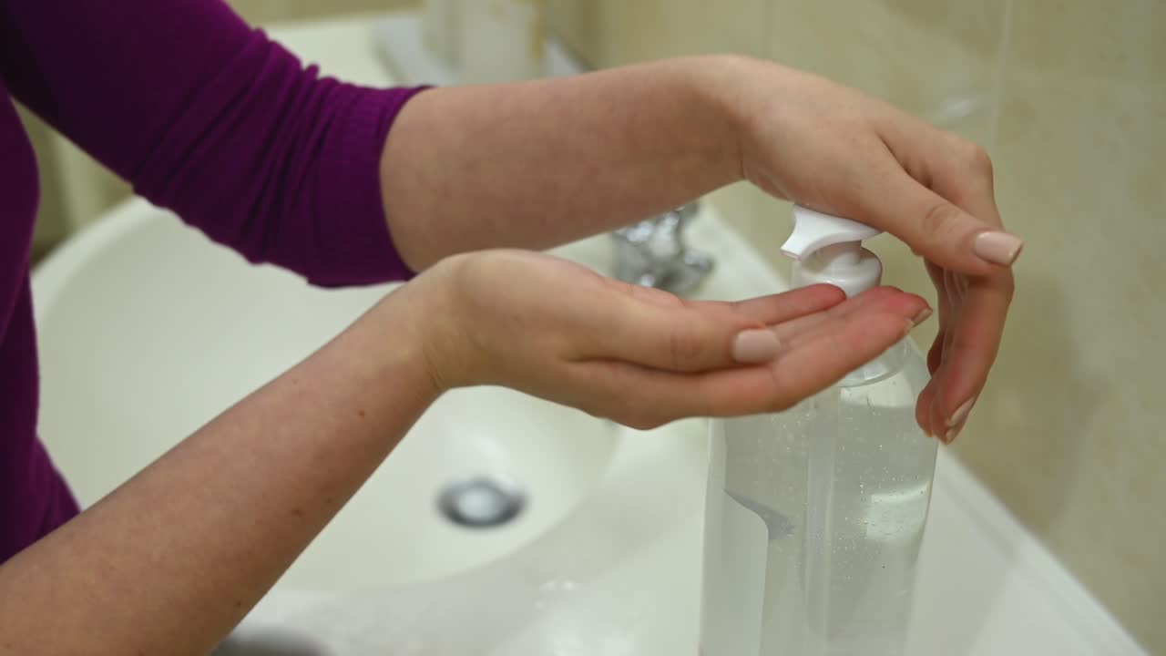 Woman washing hands with soap under running water in a bright bathroom sink