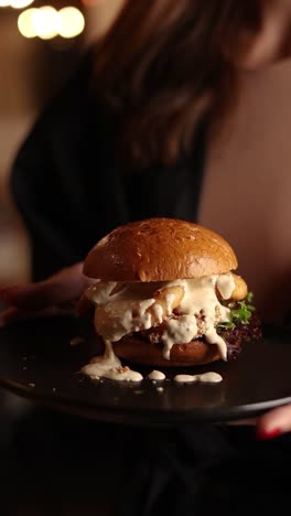 woman holding a delicious burger on a plate