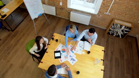 business meeting at loft shared space. team talking, woman manager giving direction to people. top view.