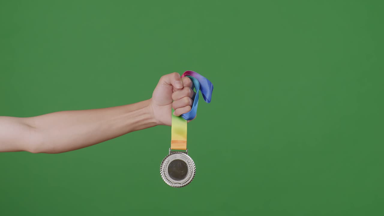 mano sosteniendo una medalla de plata con una cinta de colores en una pantalla verde