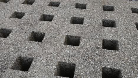 repeated geometric stone square holes carved in granite marble surface dolly right