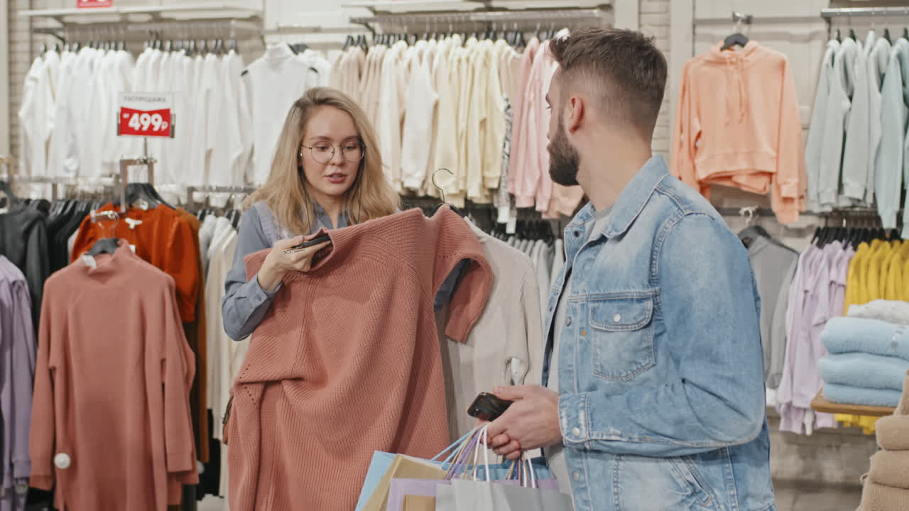 Annoyed Man Shopping For Clothes With Girlfriend