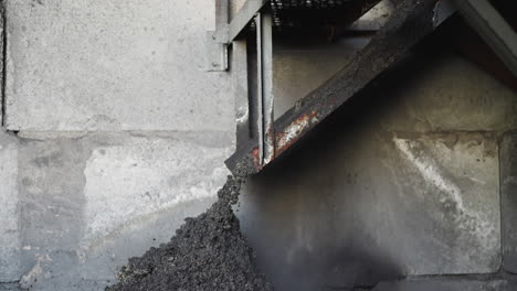Pouring-coal-slag-from-metal-feeder-in-industrial-storage