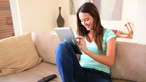 Hübsche-Brünette-Entspannt-Auf-Dem-Sofa-Mit-Ihrem-Tablet-PC