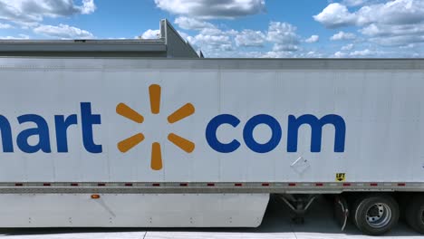 commercial drone shot of walmart com truck trailer parking at warehouse. sunny day with clouds in industrial area of american town. closeup aerial.