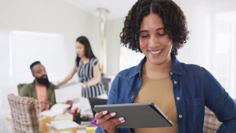 Happy-biracial-woman-using-tablet,-working-with-diverse-male-and-female-friend,-in-slow-motion