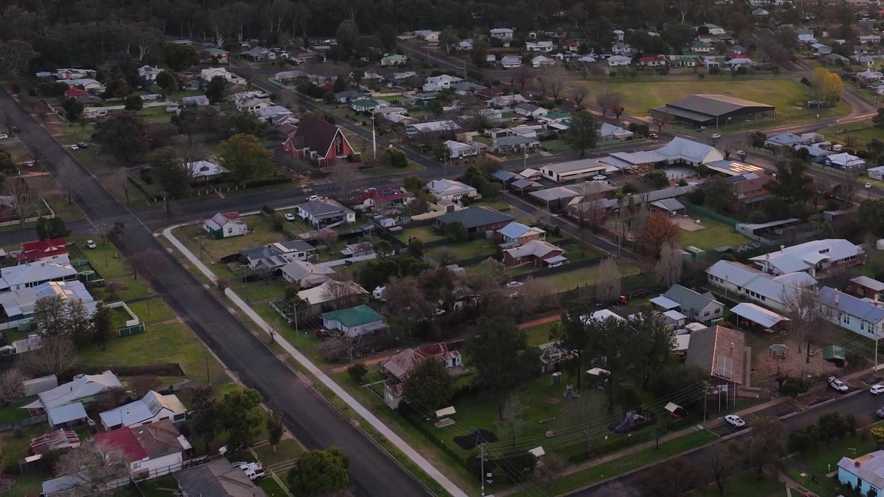 Ripresa aerea con drone su strade residenziali e case durante l'ora d'oro a Coonabarabran, Australia