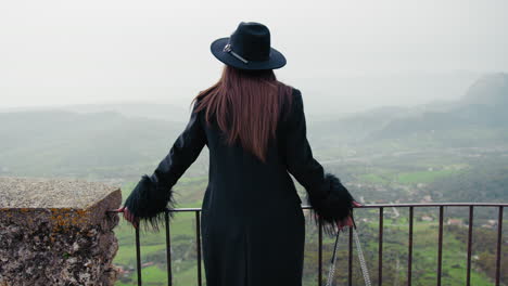 woman dressed in black coat watching the natural landscape down the railing