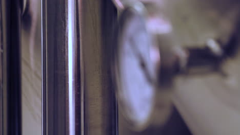 rack focus from background to a close-up of a temperature gauge mounted on a stainless steel fermentation tank in a brewery
