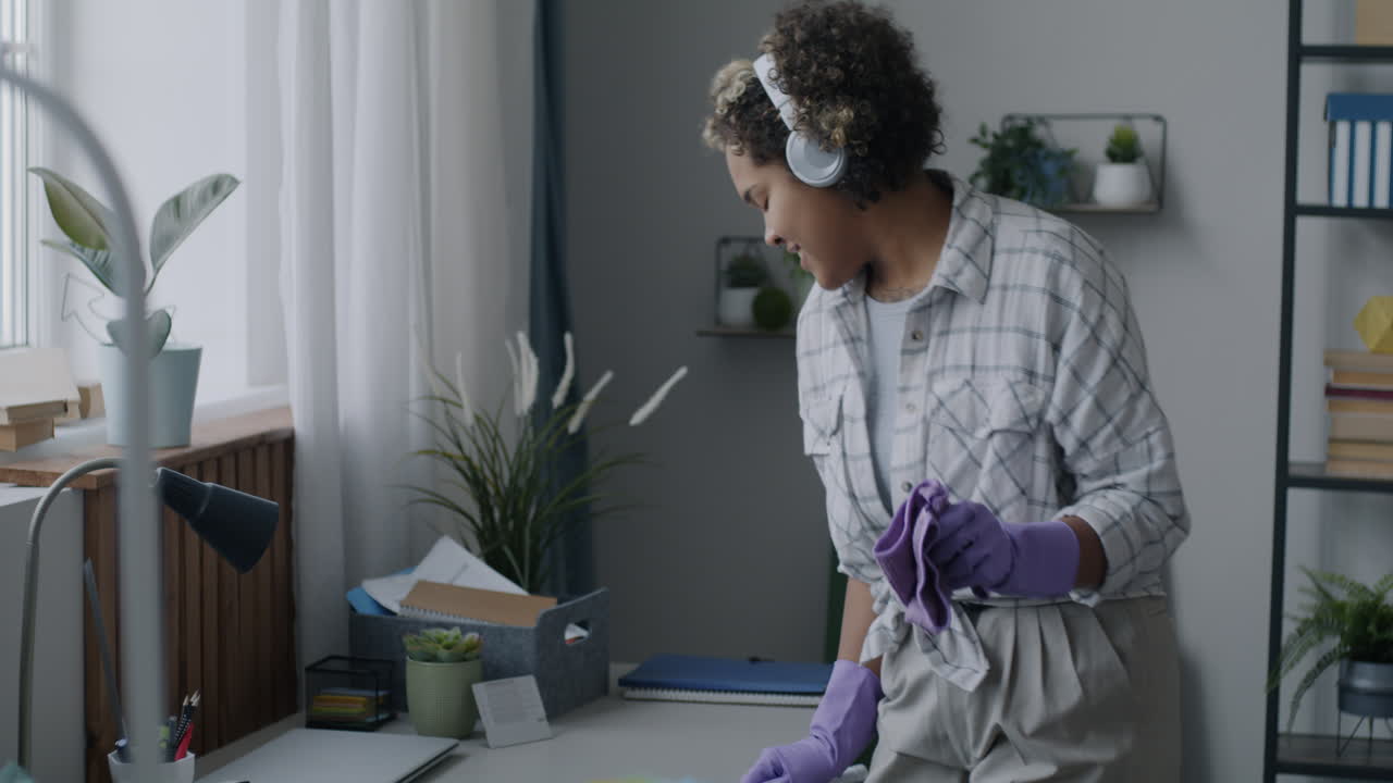Woman Cleaning Her Home Office While Listening to Music