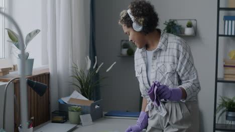 woman cleaning her home office while listening to music