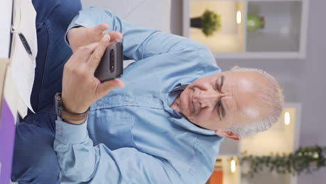 Vertical-video-of-The-old-man-who-gets-angry-and-upset-at-the-incoming-phone-message.