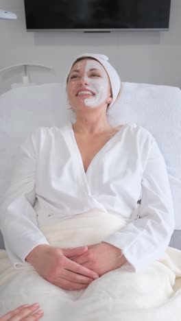 vertical video. relaxed middle-aged woman lying in a beauty salon with a mask on her face. anti-aging care.