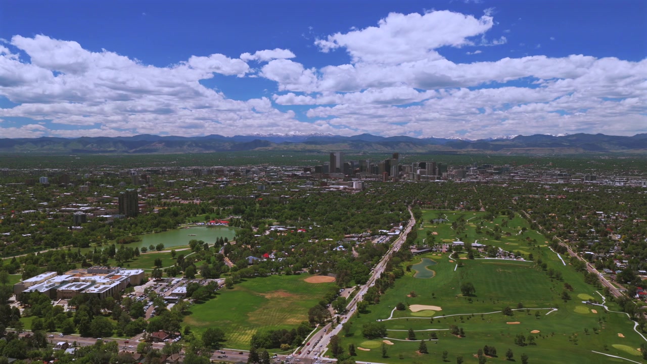 Campo da golf di City Park, centro di Denver, Colorado, vista aerea con drone, Montagne Rocciose della Front Range innevate, paesaggio urbano primaverile, skyline, grattacieli, edifici, paesaggio, cielo blu mattutino, nuvole, cerchio a sinistra.