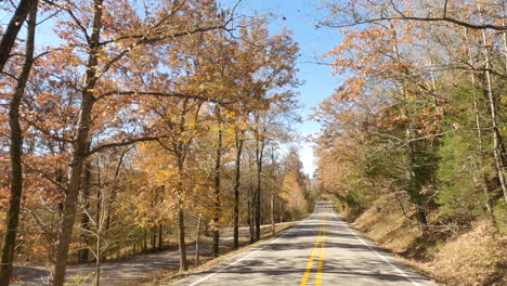 driving into empty asphalt road during autumn near devil's den state park, arkansas usa