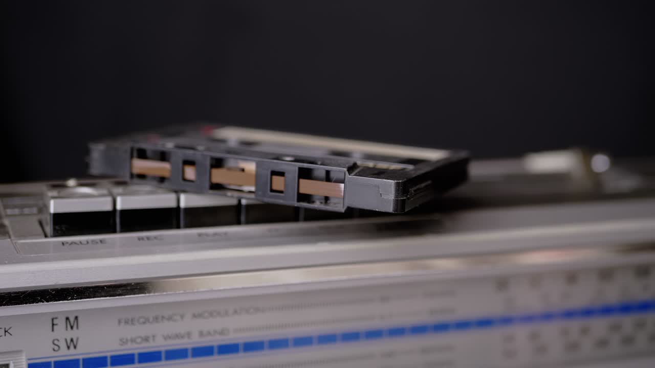 남성 손은 레트로 테이프 레코더의 버튼에 누워있는 오래된 오디오 카세트를 니다.