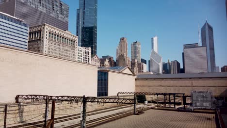 Walking-Shot-of-Downtown-City-Skyline-and-Railroad-Tracks-Blue-Sky