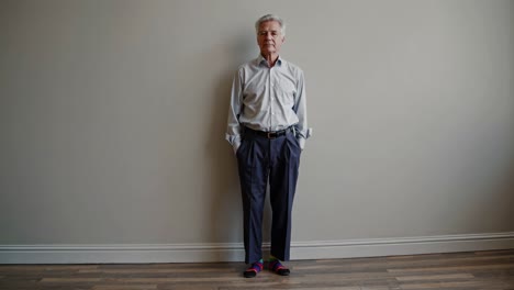 older man standing against a wall