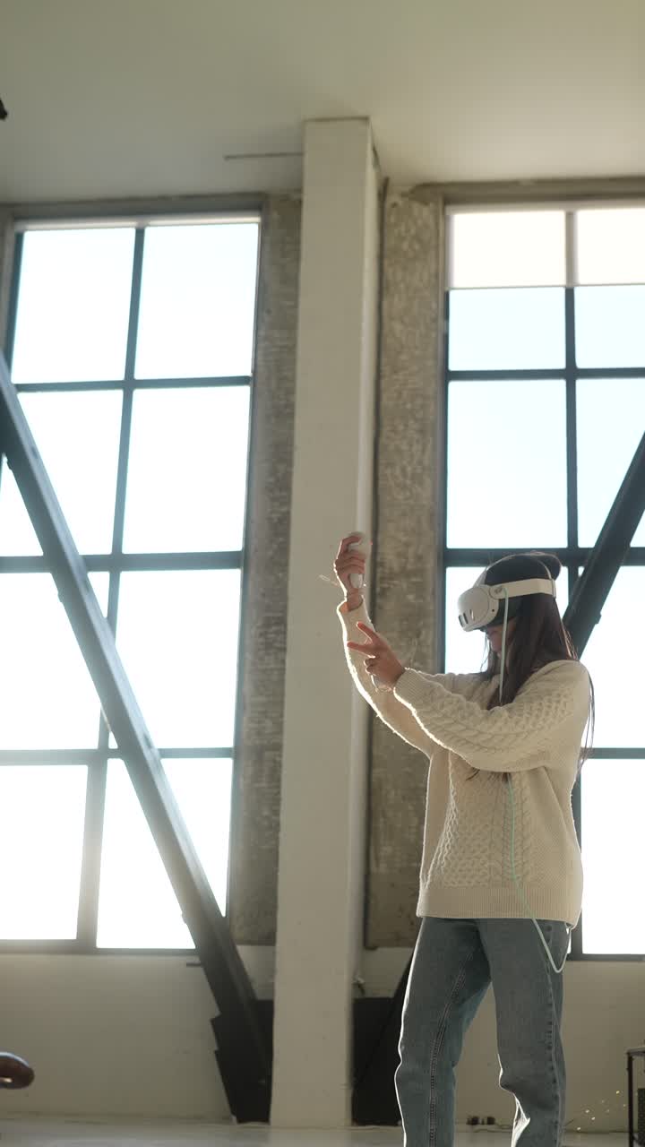 Mujer con gafas de realidad virtual y mandos jugando a un juego de RV en una habitación luminosa
