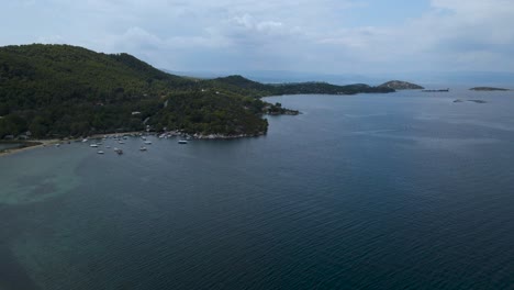 4K-Drone-clip-slowly-moving-backwards-over-a-shallow-water-and-beach-in-the-bay-of-Vourvourou,-in-Chalkidiki,-northern-Greece