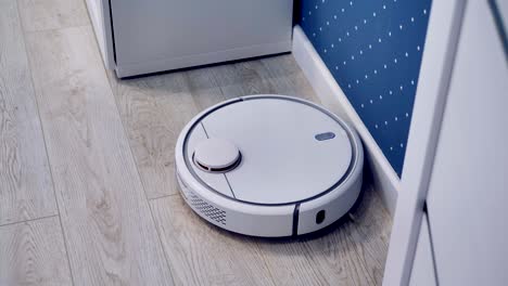 a close top view on a robotic vacuum cleaner dusting a corner.