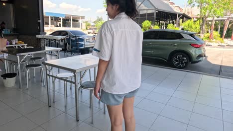 person walking towards and sitting at a cafe table