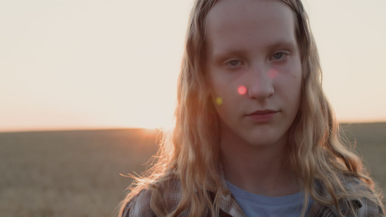 retrato de una niña adolescente con el fondo de un campo de trigo donde se pone el sol