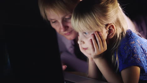 Mother-And-Daughter-Lying-On-The-Bed-Use-A-Laptop