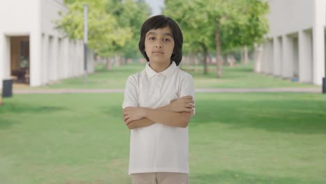 confident indian boy standing crossed hands in park